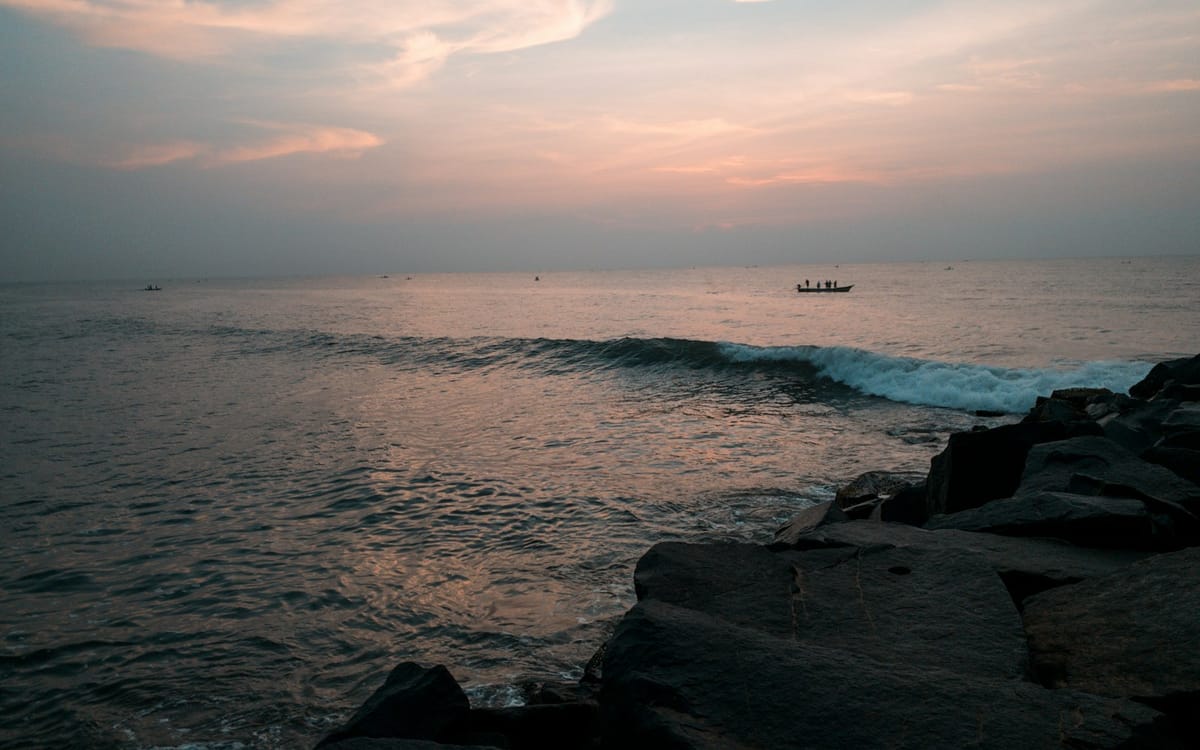 Fishing boats pulled up on a wide empty beach beside a small coastal village