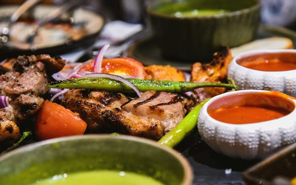 A cook tending skewers of kebabs over coals at a busy Lucknow street stall