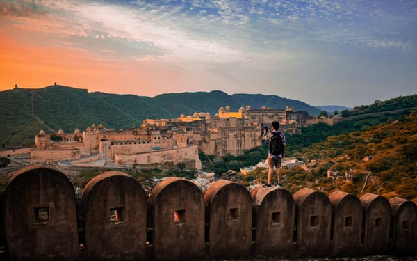 A sandstone fort wall glowing gold above a Rajasthan town at sunset