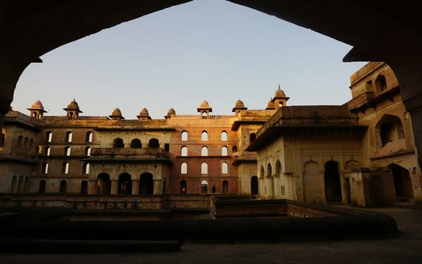 A courtyard of an old sandstone haveli with carved balconies and potted plants