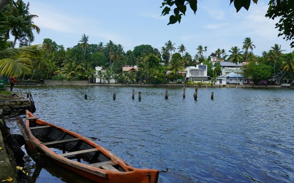 A wooden canoe on a narrow palm-lined backwater canal in Kerala
