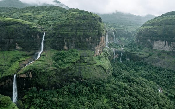 A waterfall in full flow surrounded by dripping green forest in the Western Ghats